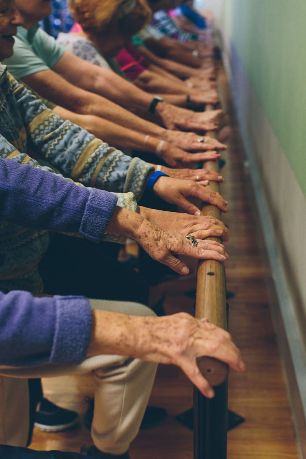 Older adults participating in a YMCA senior fitness class using a barre for support