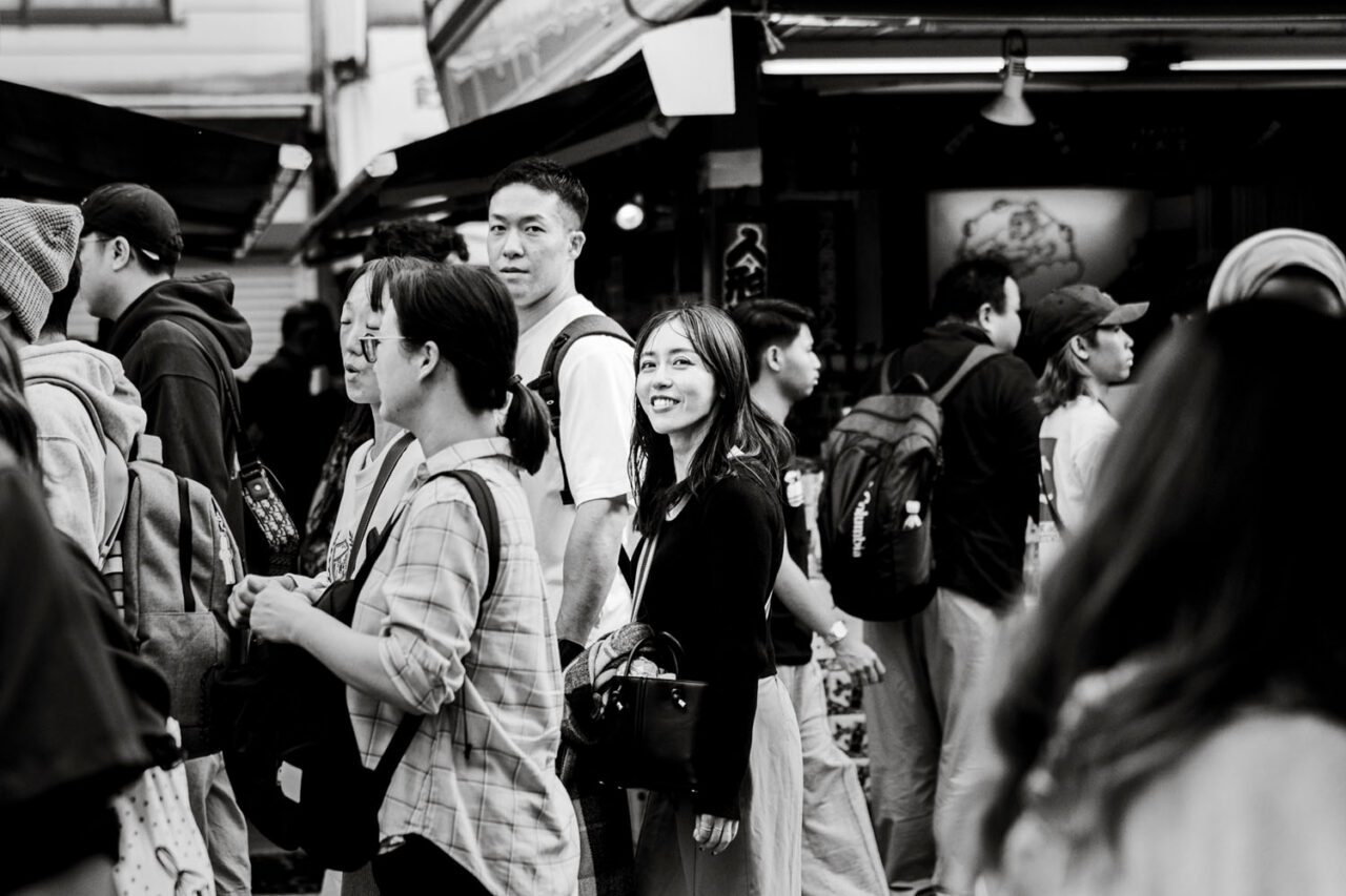 Smiling woman in a crowded Asakusa street scene photographed in black and white