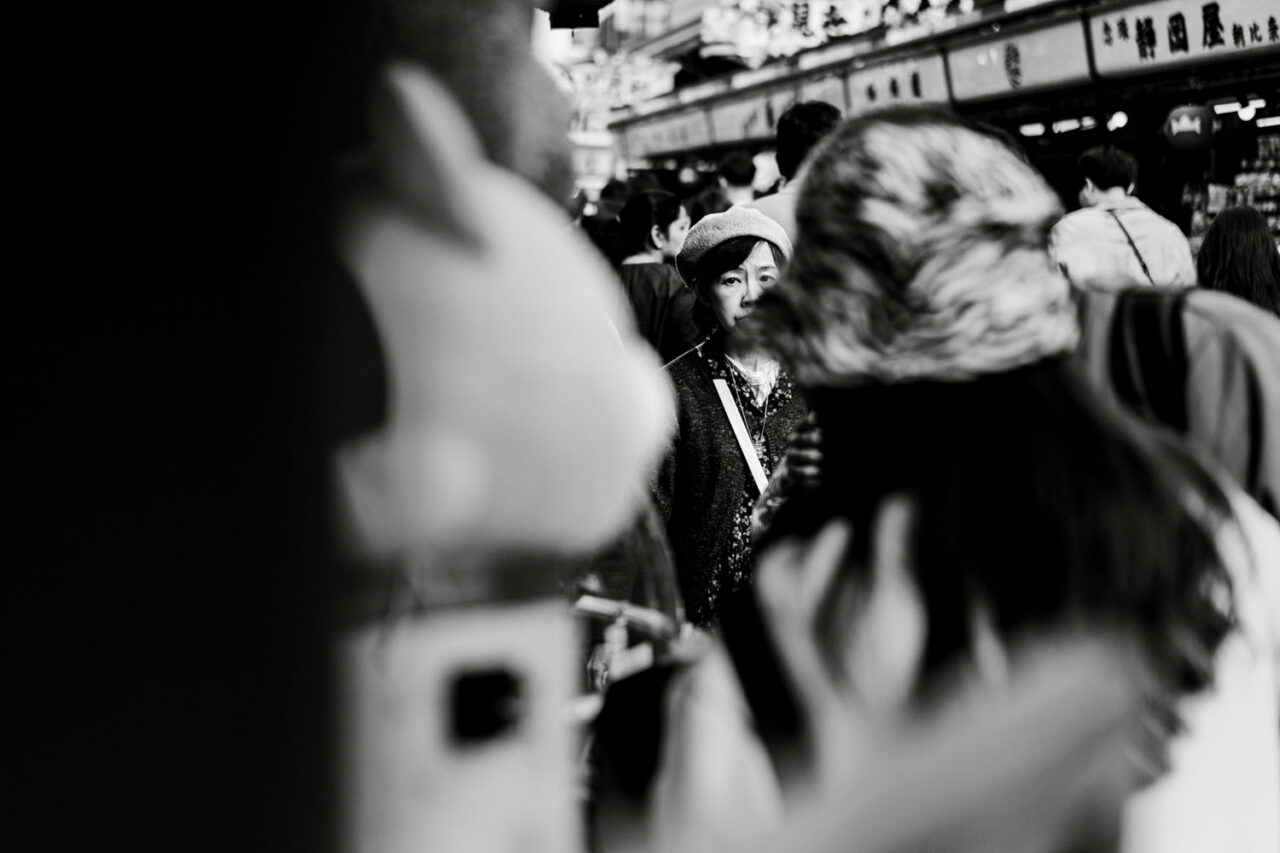 Woman framed between people in a busy Asakusa crowd in black and white