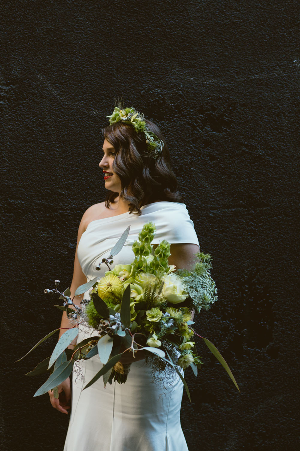 Portrait of a bride wearing a floral crown and holding a lush green wedding bouquet designed by Botanics of Melbourne.