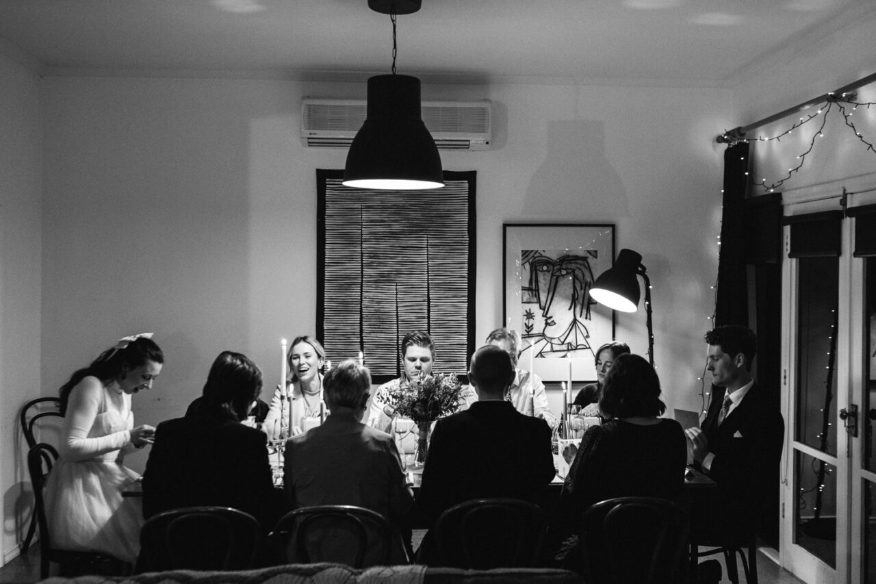 Guests seated around a long table at a candlelit wedding dinner inside a Daylesford Airbnb.