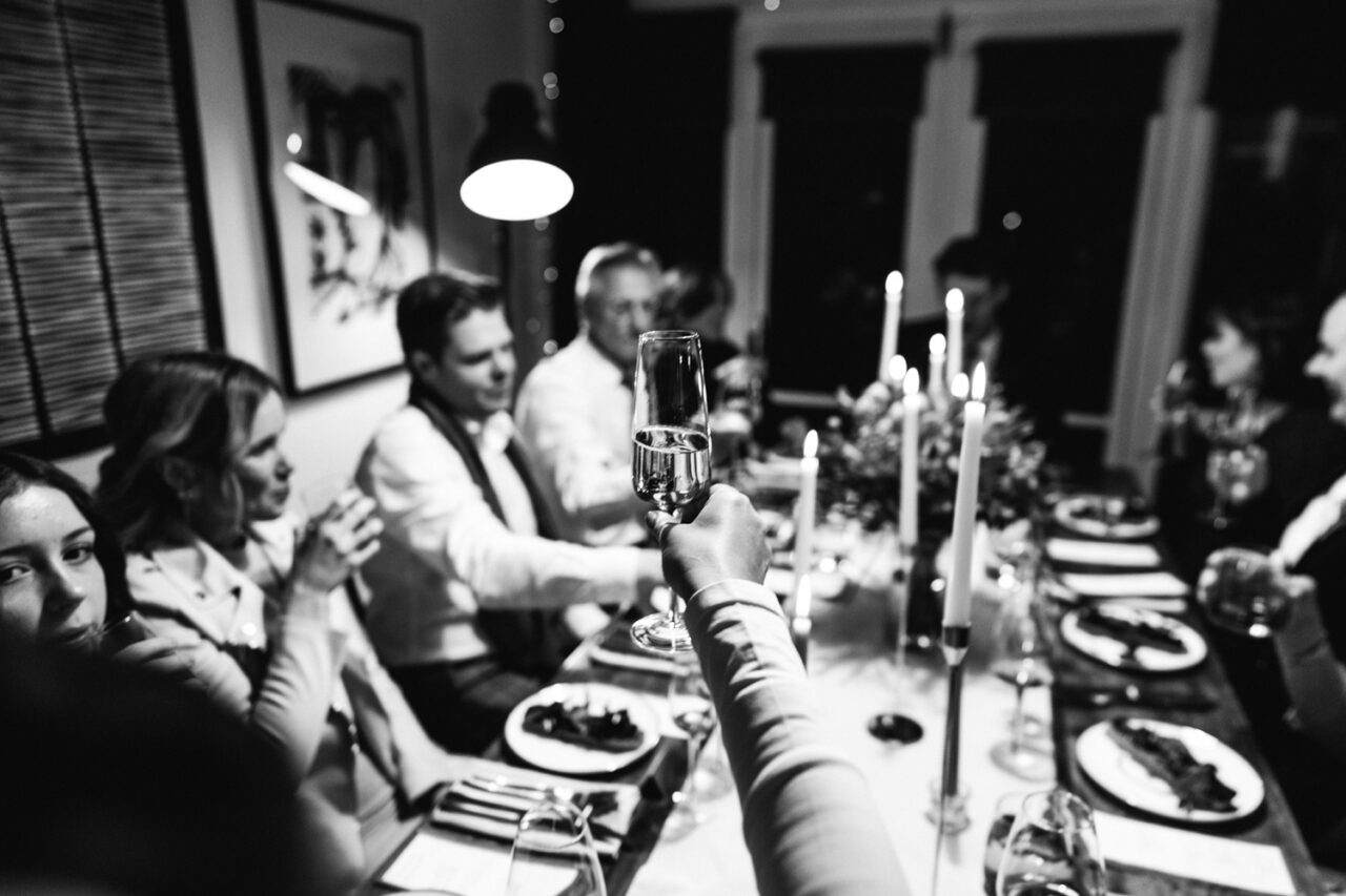 Close up of a champagne glass raised in a toast during a wedding dinner celebration.
