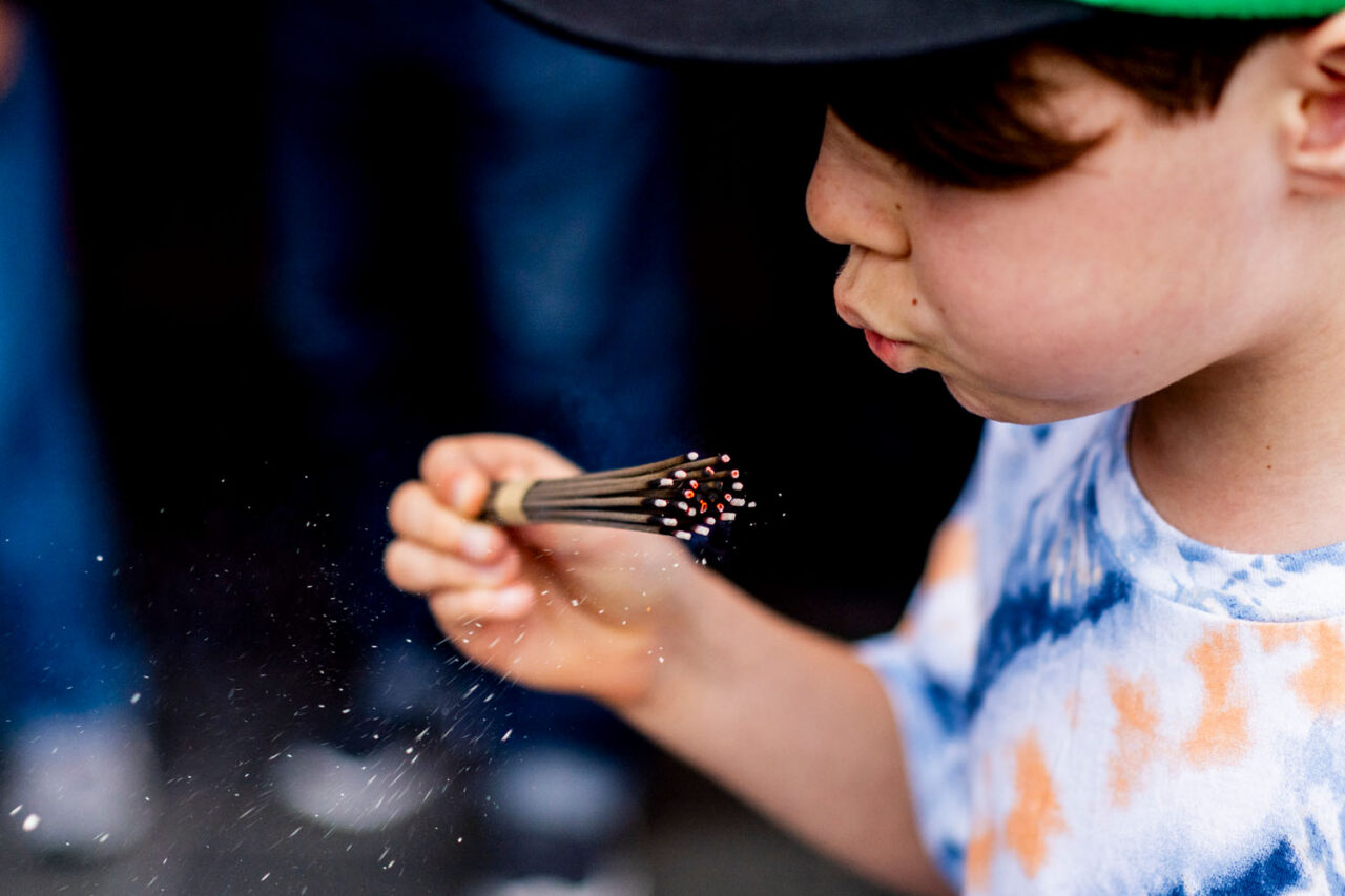 Child blowing gently on incense sticks at Sensoji Temple in Asakusa