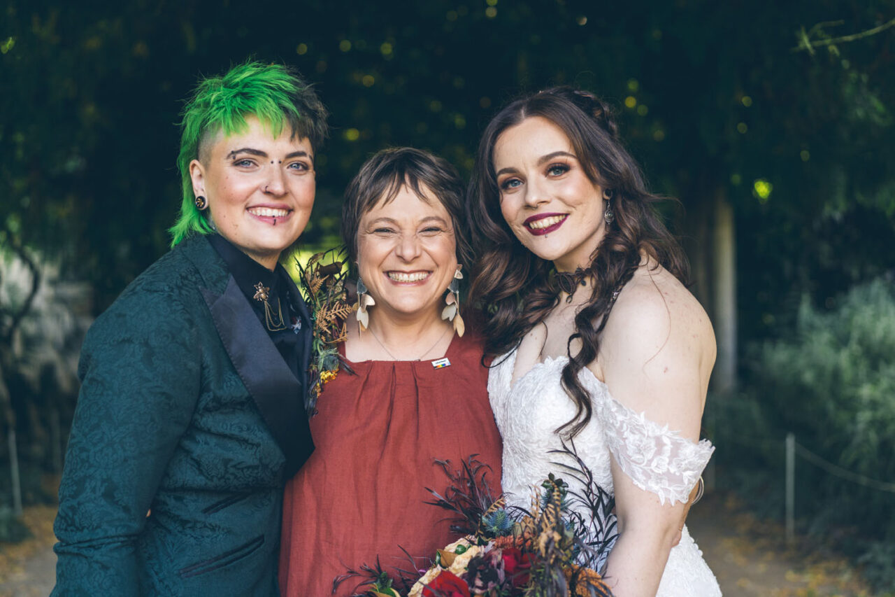 Dee Wild posing with newly married queer couple after their ceremony