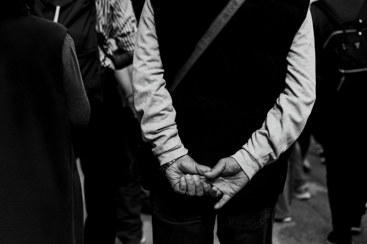 Person standing with hands clasped behind their back in a crowded Asakusa street