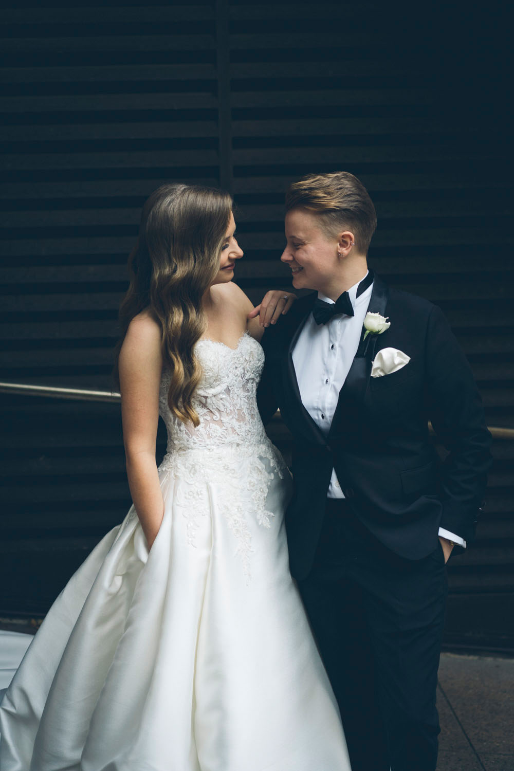 Queer Couple portrait featuring a bride in a wedding dress beside their partner wearing a tailored women’s wedding suit by Isadora Nim.