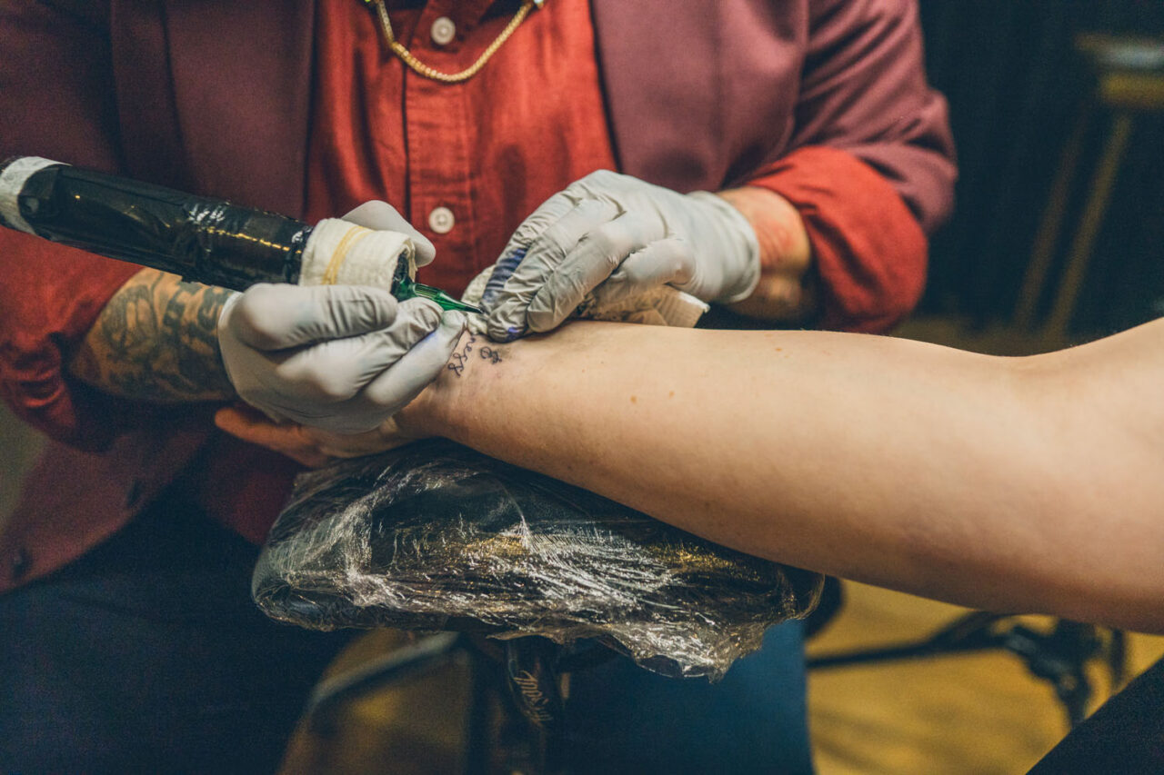 Tattoo artist Lee Stain giving a small tattoo to a guest during a wedding reception in Melbourne.