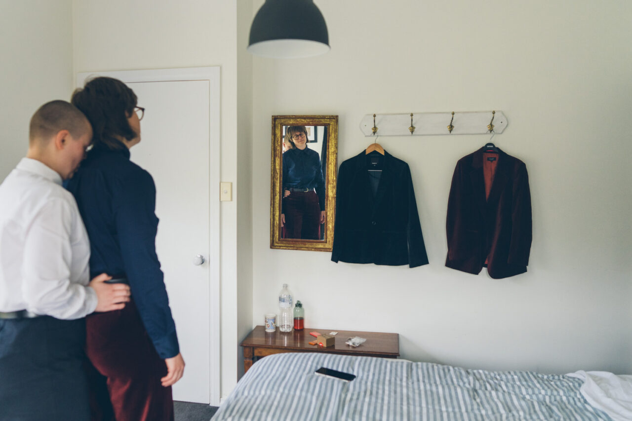 Tailored suits hanging beside a mirror while the couple get ready for their intimate Daylesford wedding.