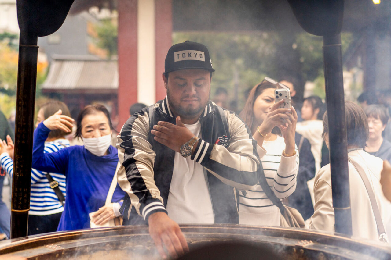 Visitor placing incense into a burner at Sensoji Temple in Tokyo