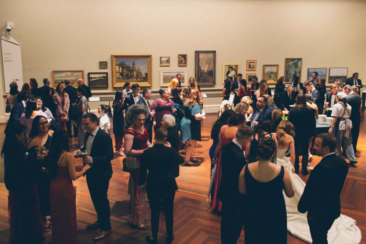 Wedding guests mingling during a reception inside the State Library Victoria gallery in Melbourne.