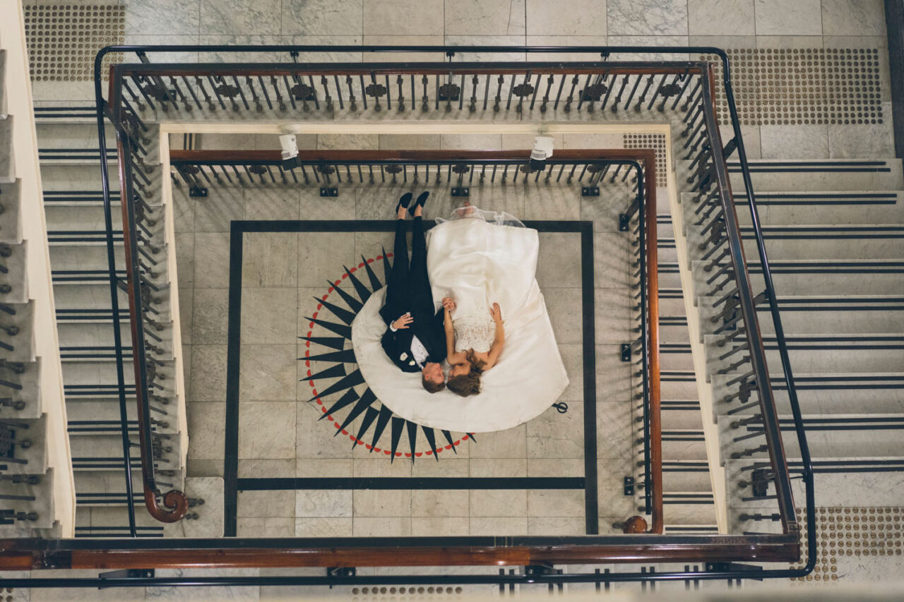 Couple lying together on the marble floor inside the State Library Victoria staircase during their wedding portraits.