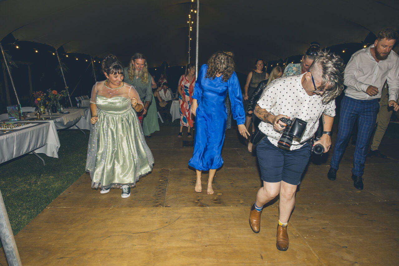 Documentary wedding photographer dancing with guests while photographing the reception dance floor at a Surf Coast wedding.
