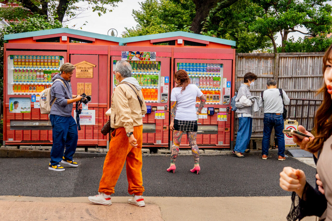 People standing in front of colourful vending machines on a street in Asakusa, Tokyo