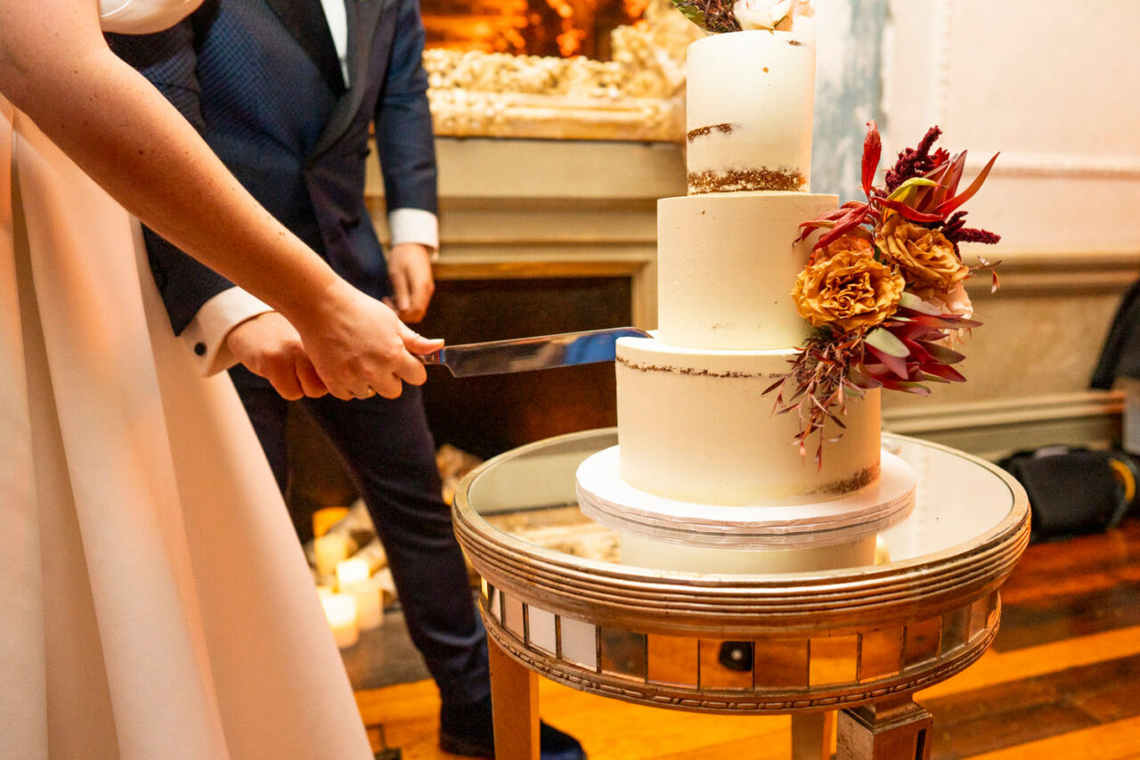 Couple cutting a modern two-tier wedding cake during their reception celebration.