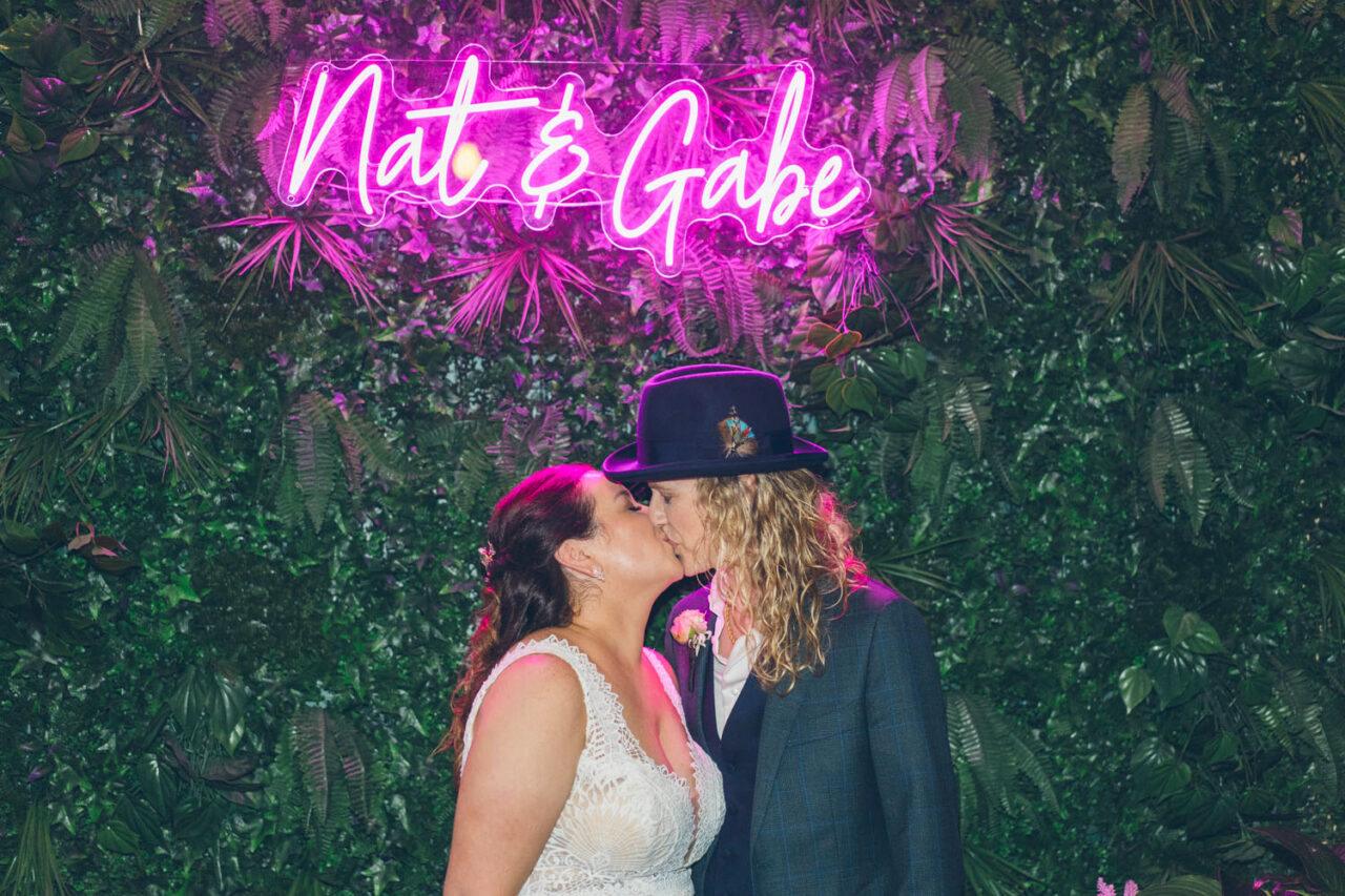 Couple kissing beneath neon “Nat & Gabe” sign during their wedding reception at Welcome to Thornbury Melbourne.