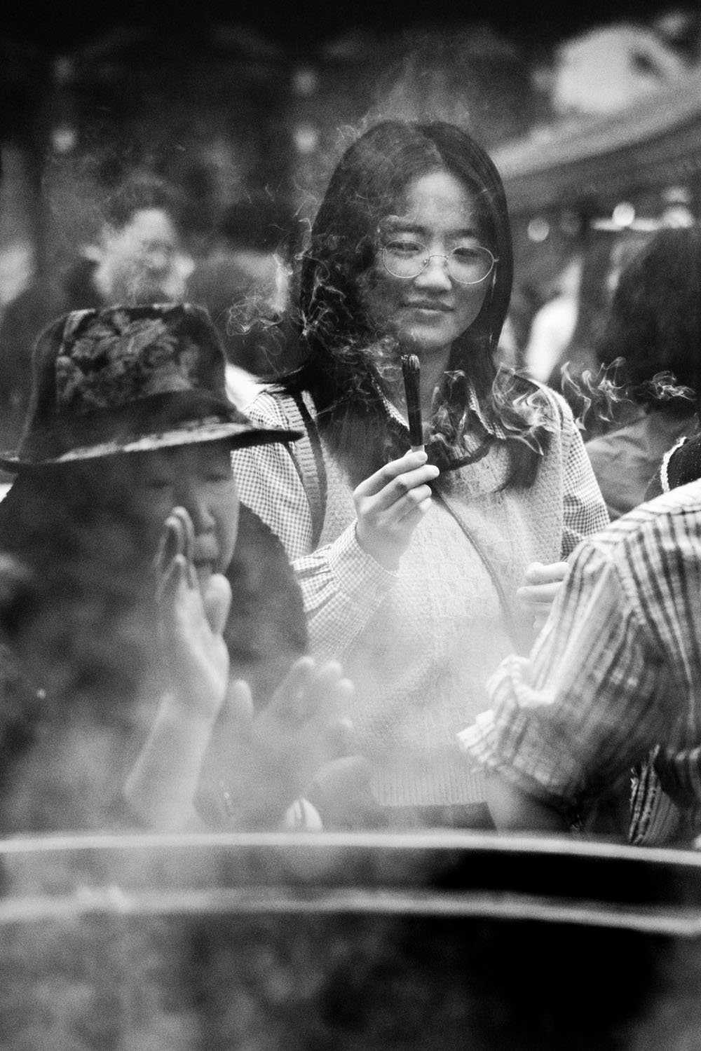 Woman holding incense surrounded by smoke at Sensoji Temple in black and white