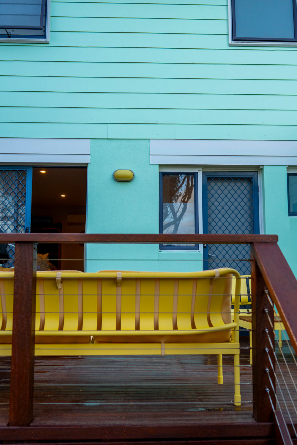 Mint green beachfront house on the Surf Coast with yellow outdoor furniture on the timber deck, photographed at 8am during a documentary Your Story session