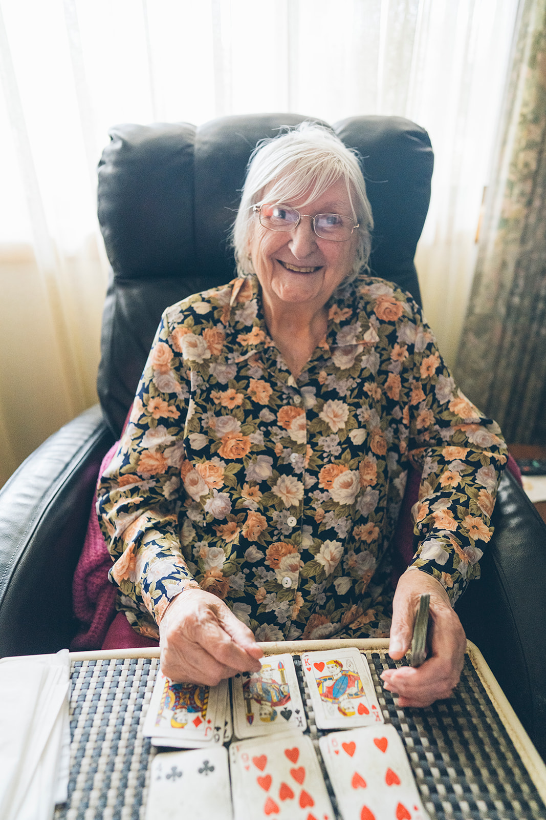 Elderly woman smiling while playing cards in her family home, documentary portrait photography Melbourne
