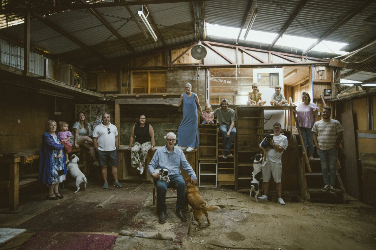 Extended family group portrait inside a rustic shed with dogs and children, documentary family home photography Surf Coast