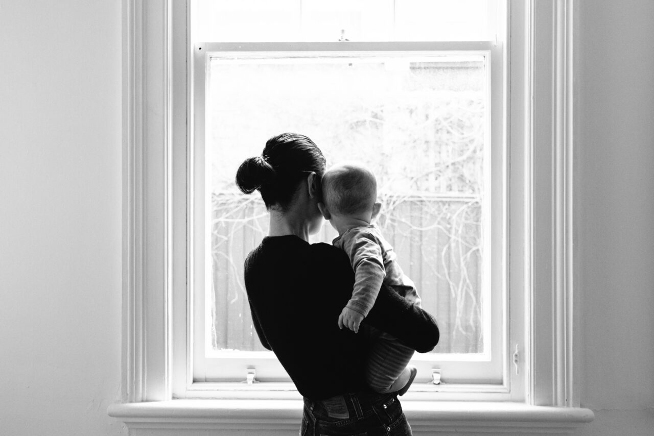 Black and white silhouette of a mother holding a baby at a window, documentary family home photography Melbourne