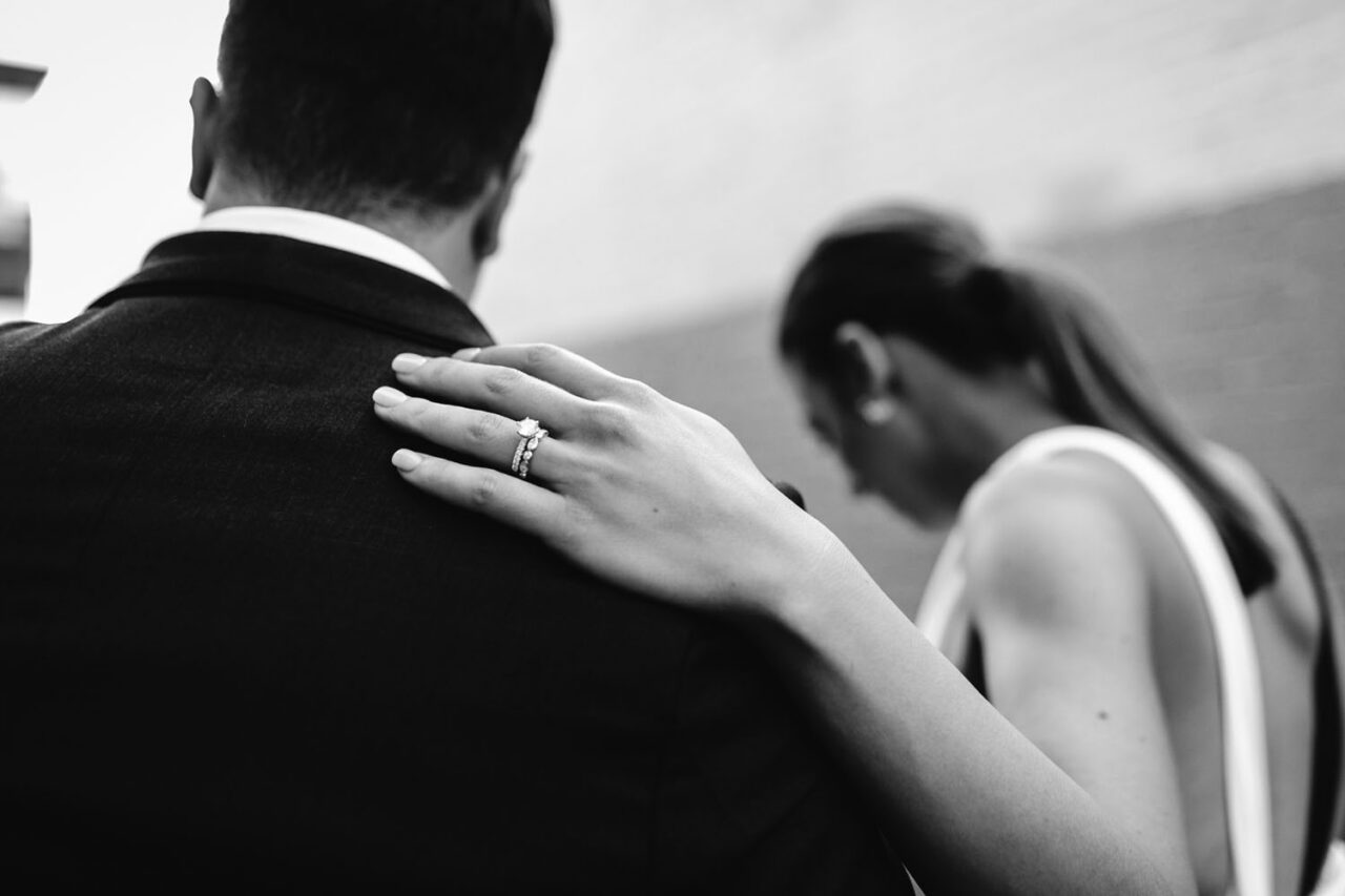 Close up of bride's hand resting on groom's shoulder showing wedding and engagement rings during Melbourne wedding ceremony