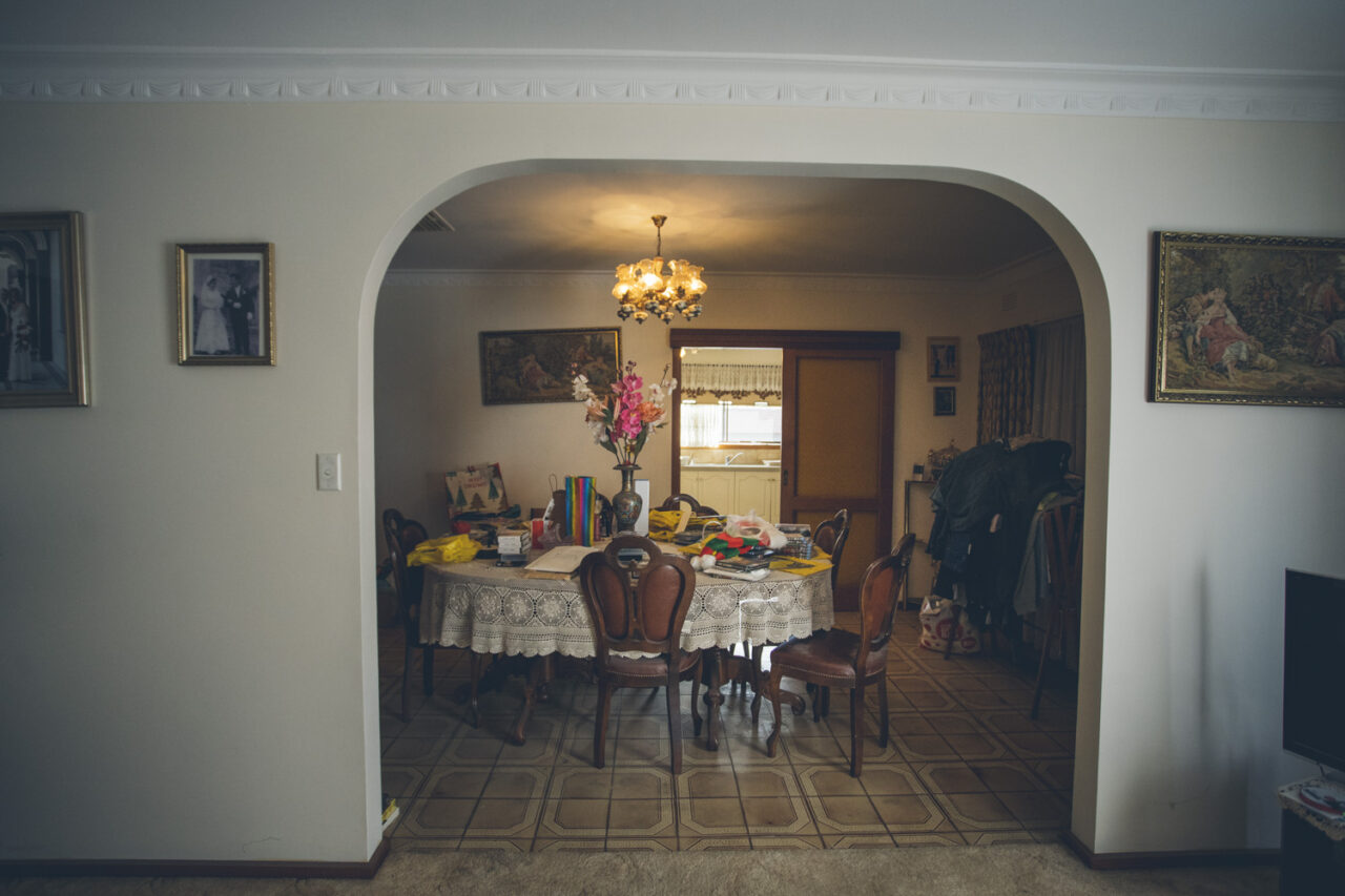 Dining room of a Melbourne family home with lace tablecloth and family photographs, captured during a deceased estate photography session