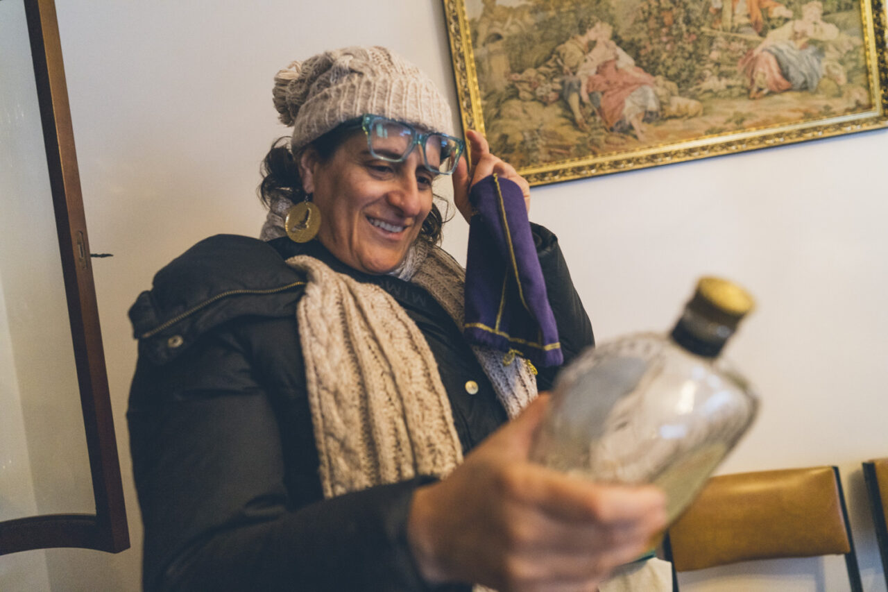Woman smiling and holding a glass bottle found during a deceased estate documentary photography session in Melbourne