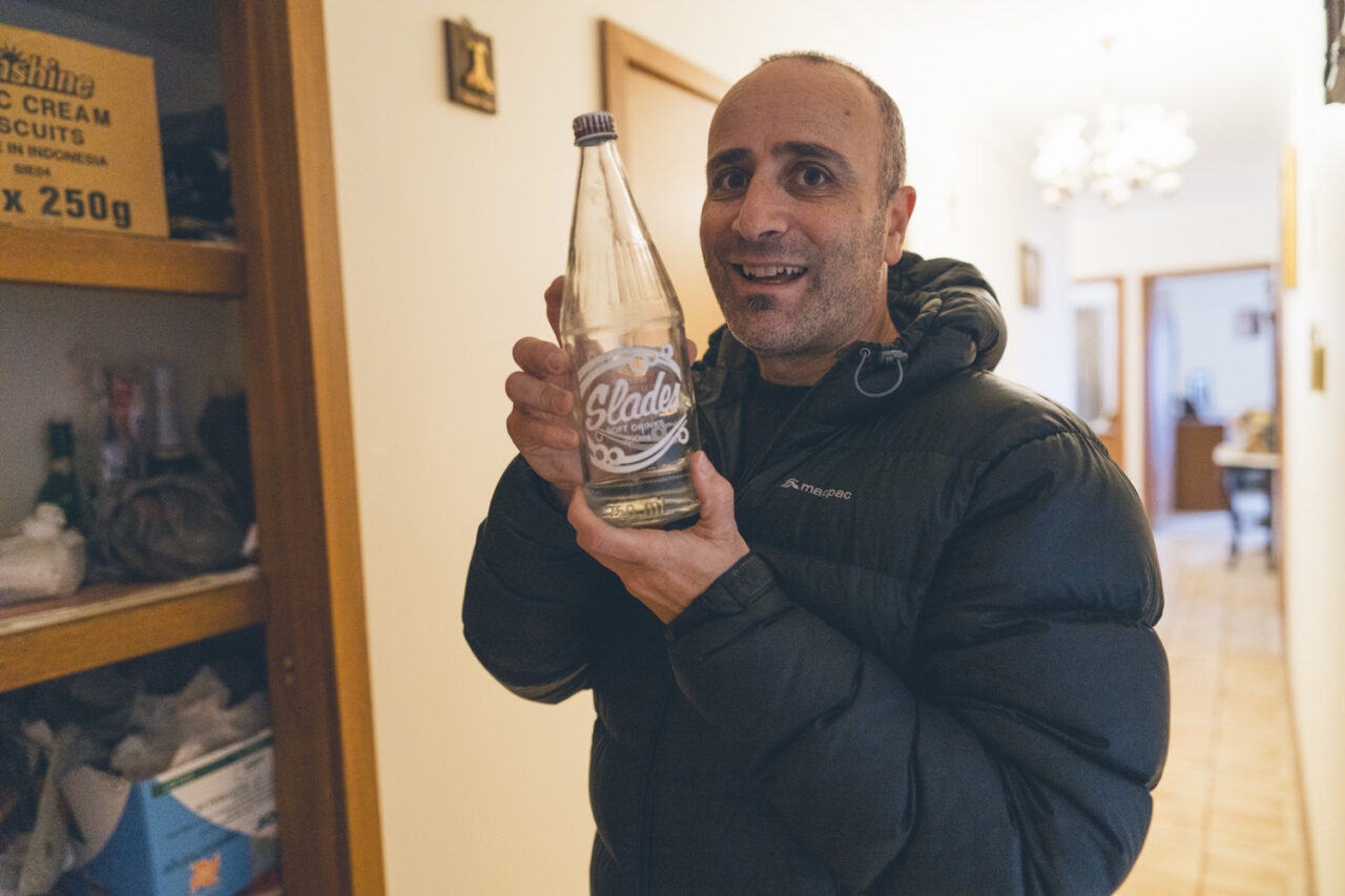 Family member holding up a vintage Slades soft drink bottle found during a deceased estate documentary session in Melbourne