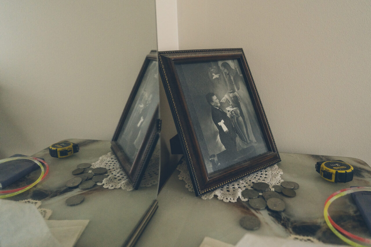 Framed black and white photograph surrounded by loose coins on a doily, detail from a deceased estate documentary session