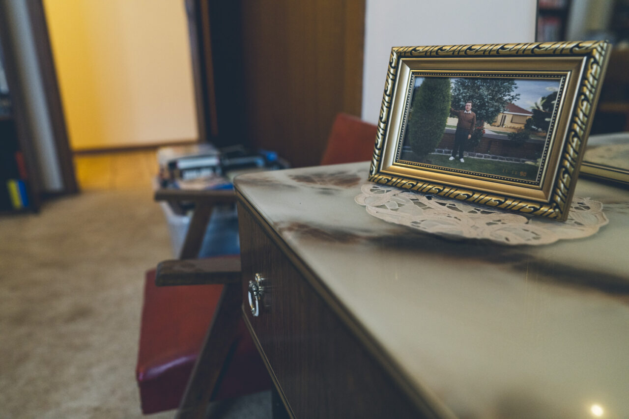 Framed photograph of a family member on a sideboard with a crocheted doily, detail from a deceased estate photography session