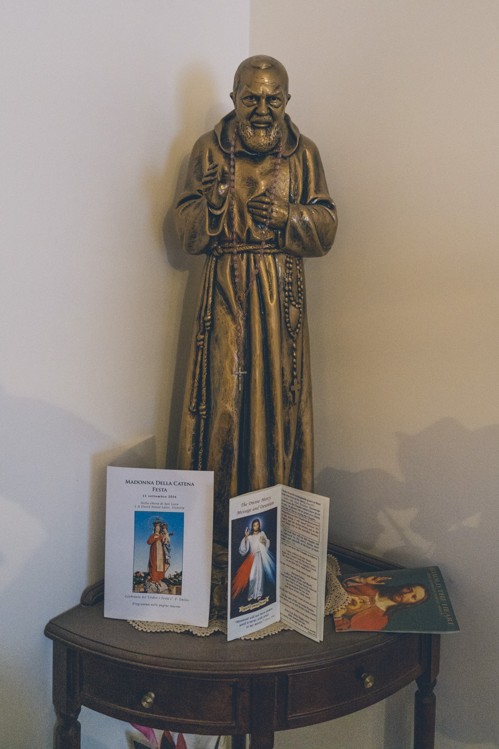 Bronze religious statue with rosary beads and prayer cards on a side table, photographed during a deceased estate session in Melbourne