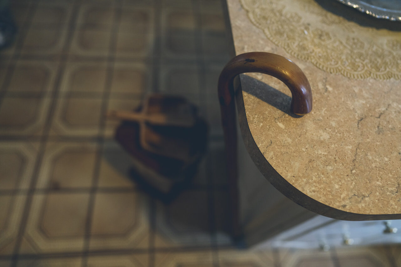  Close up of a wooden handled walking stick resting on a stone table, detail photograph from a deceased estate session