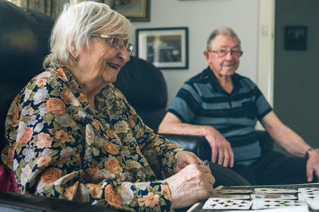 Elderly couple sitting together in their lounge room while playing cards, documentary family home photography Melbourne