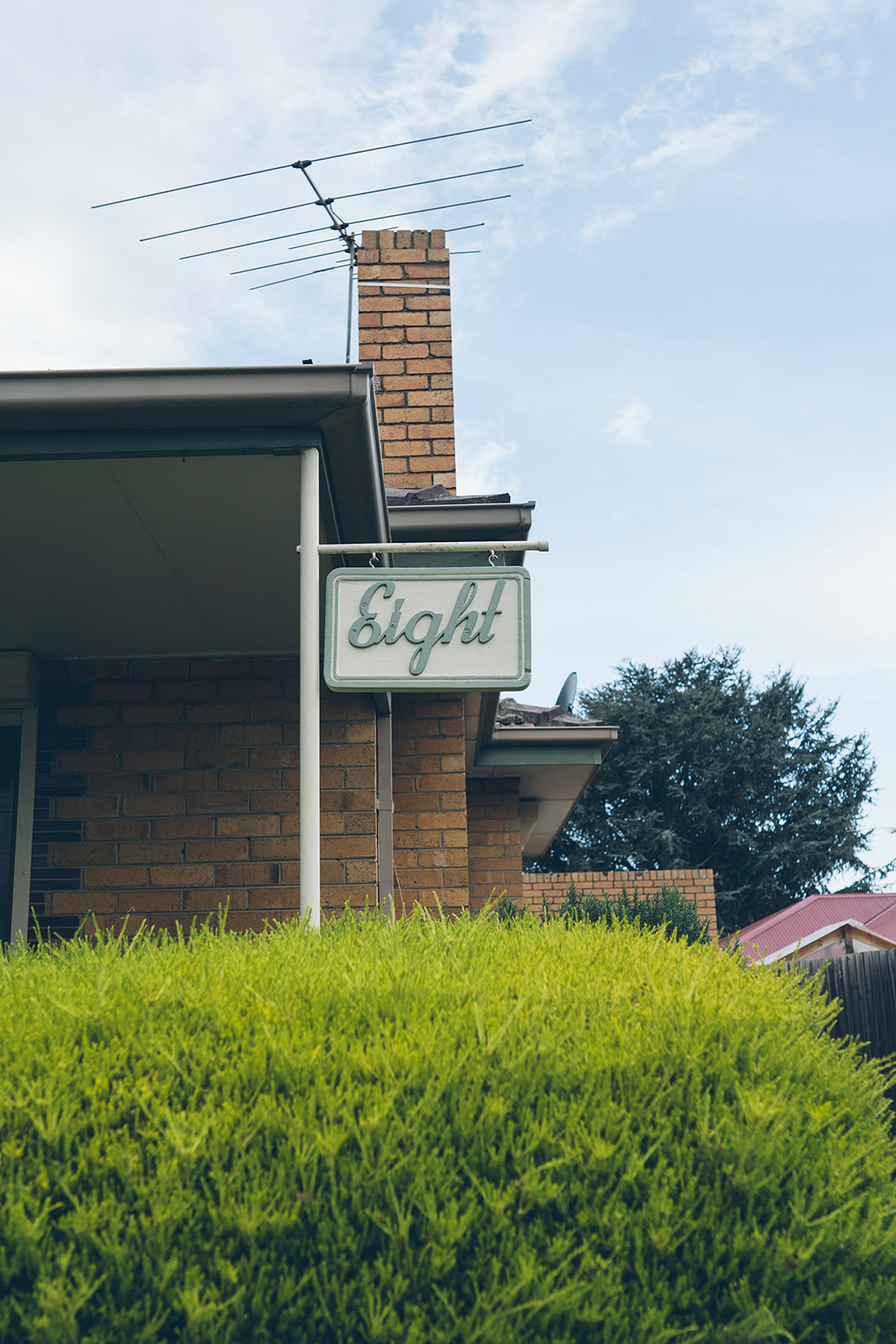 Vintage cursive house number sign reading Eight on the exterior of a brick family home, documentary photography Melbourne