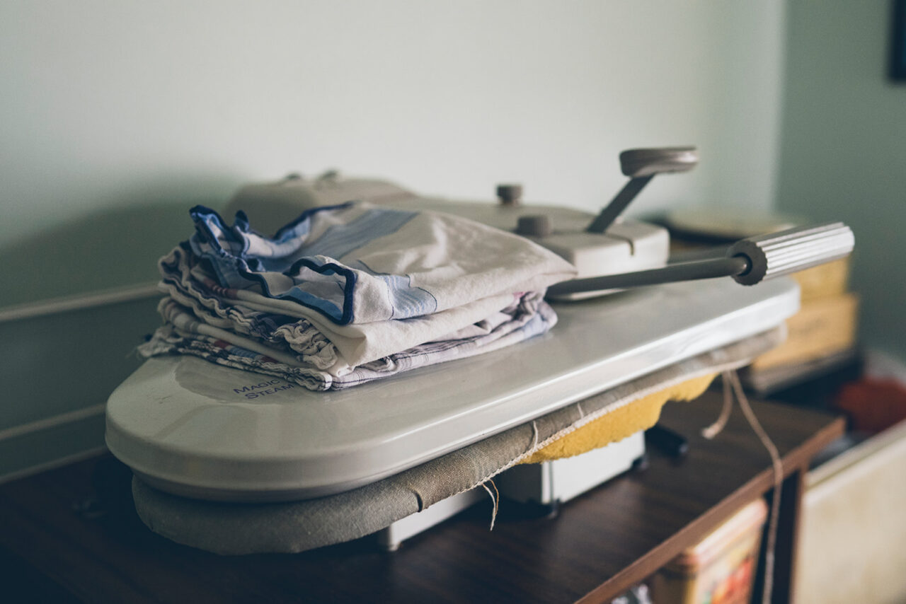Folded laundry on an ironing board, a detail of everyday domestic life captured during a family home documentary photography session