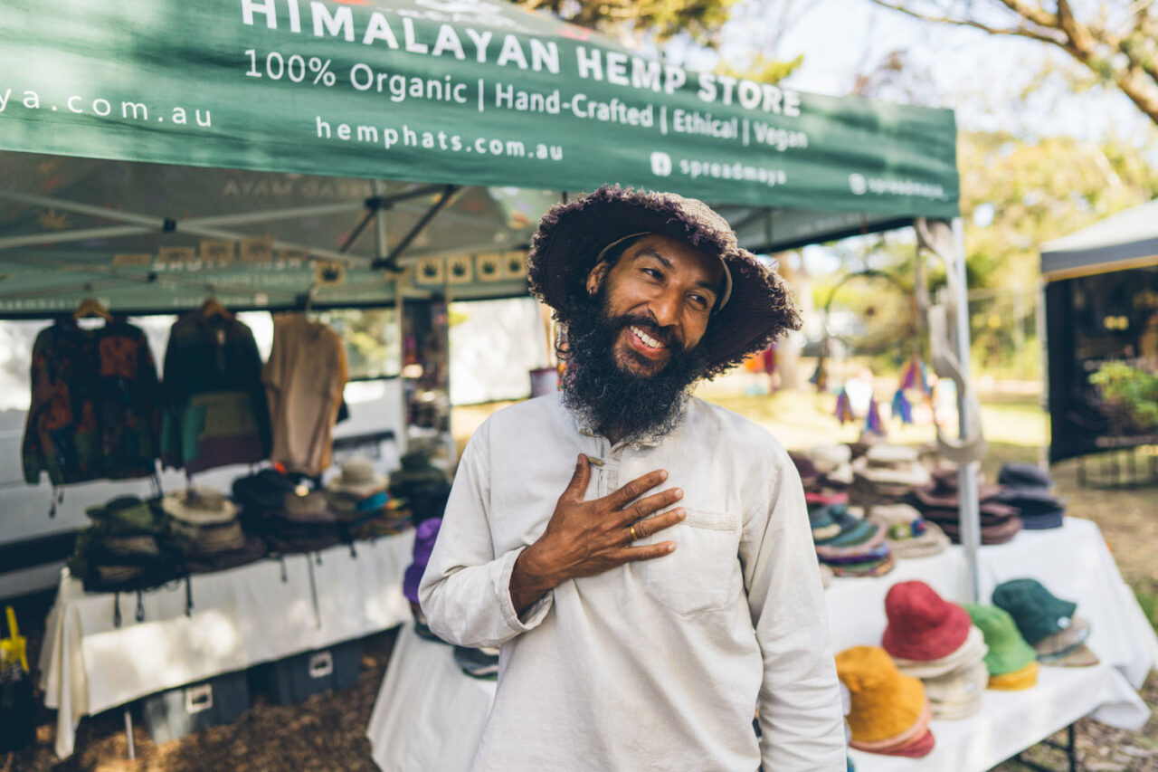 miling man with hand on heart standing in front of Himalayan Hemp Store market stall at Nightjar Markets Surf Coast, documentary brand photography by LJM Photography