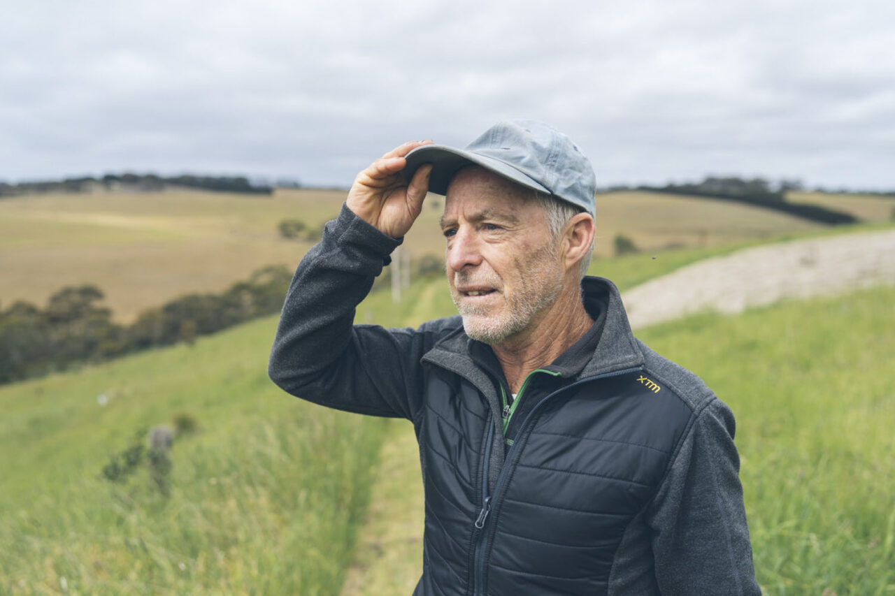 Documentary portrait of Graeme Stockton of Ashmore shading his eyes while surveying rolling green farmland on the Surf Coast Victoria, environmental personal branding photography by LJM Photography Surf Coast