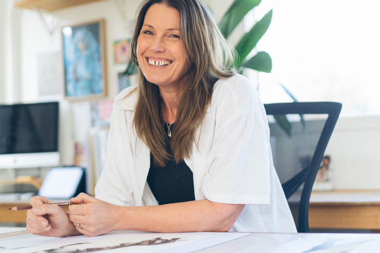 Documentary portrait of artist Kirsten Walsh of Ashmore Art laughing at her desk in her bright studio space, personal branding photography by LJM Photography Surf Coast