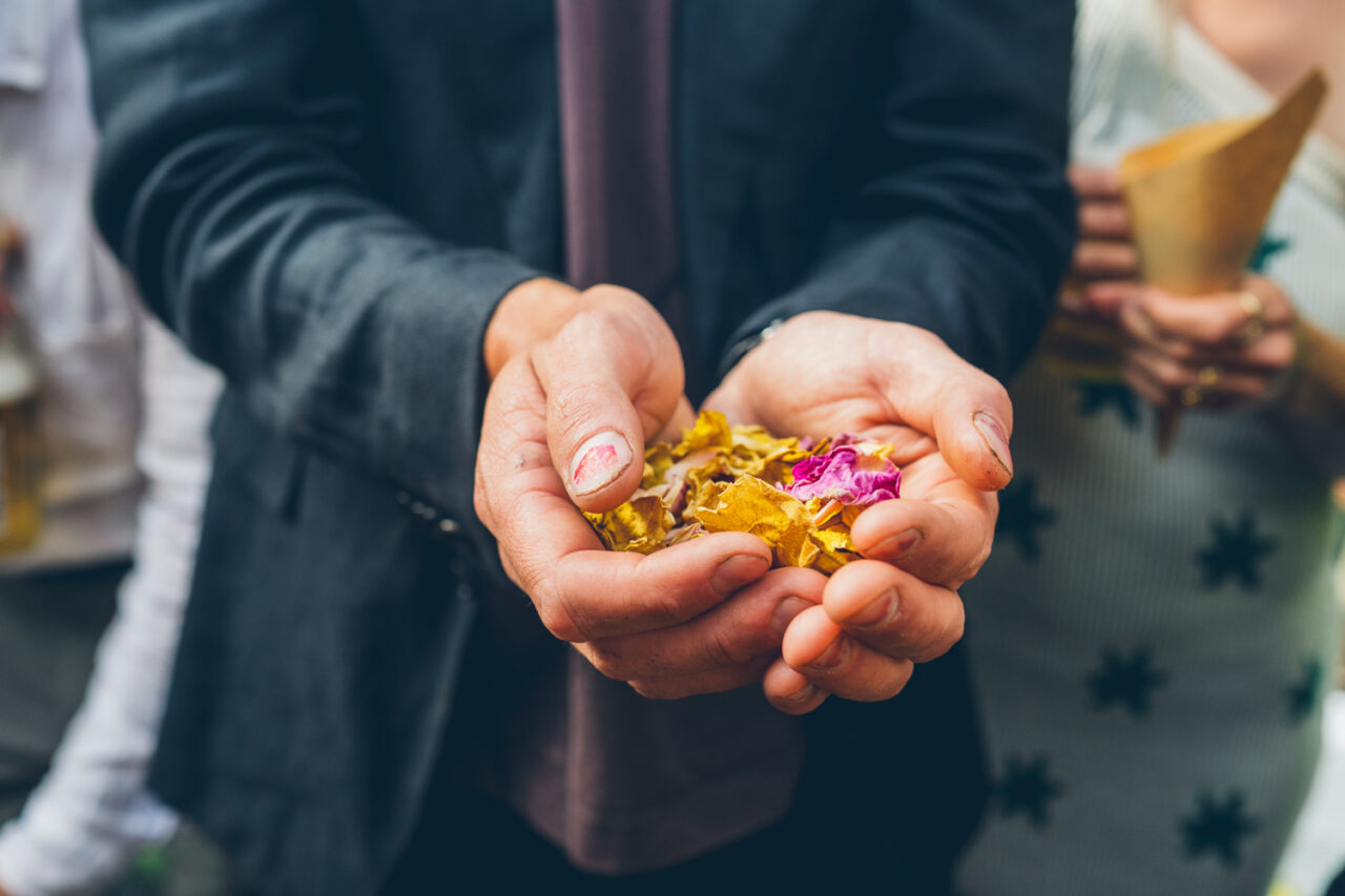 Close up of a wedding guest's hands cupping dried flower petals and confetti ready to throw at a backyard wedding on the Surf Coast