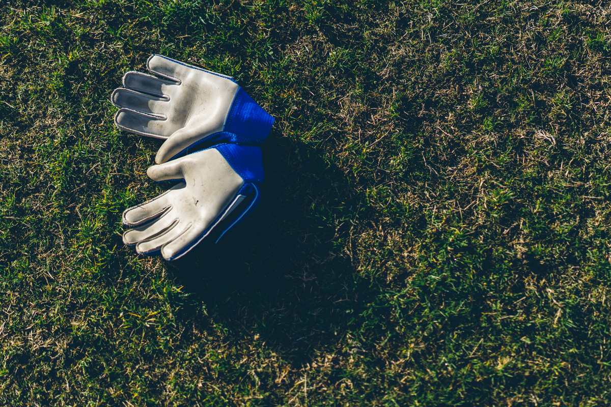 Goalkeeper gloves resting on grass in soft sunlight