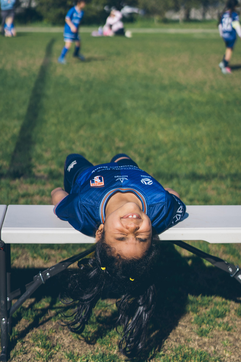 Girl lying back over a bench laughing on the sideline