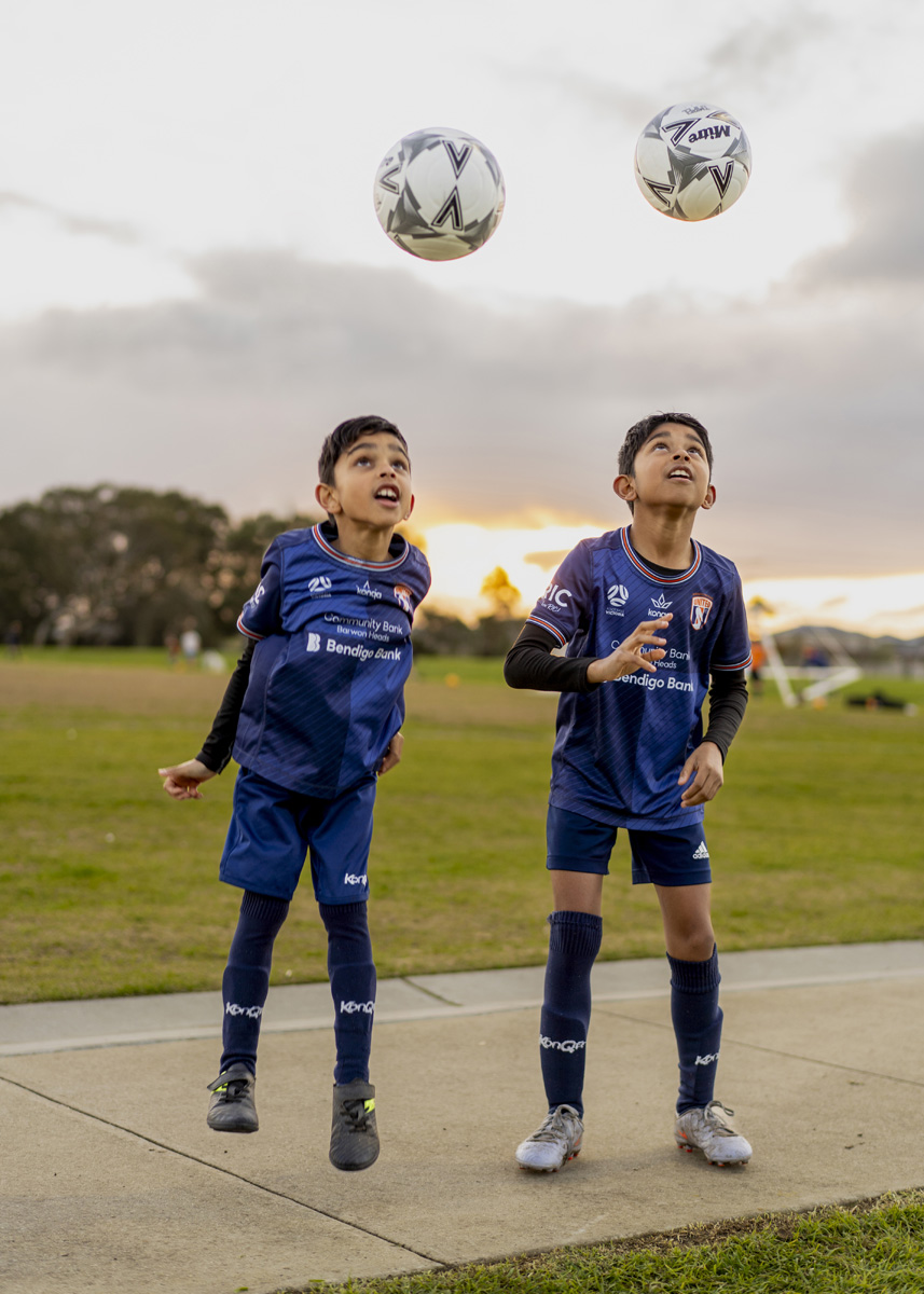 Two brothers playing with soccer balls at sunset on the Surf Coast
