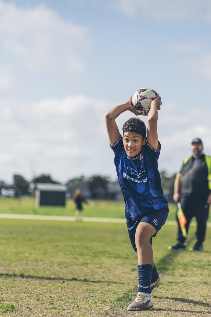 Junior soccer player taking a throw in during a match