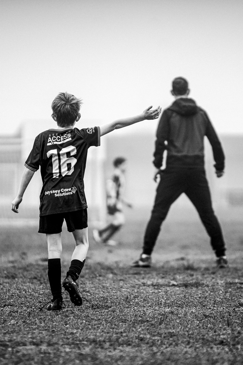 Junior soccer player signalling to his coach on a foggy morning, black and white