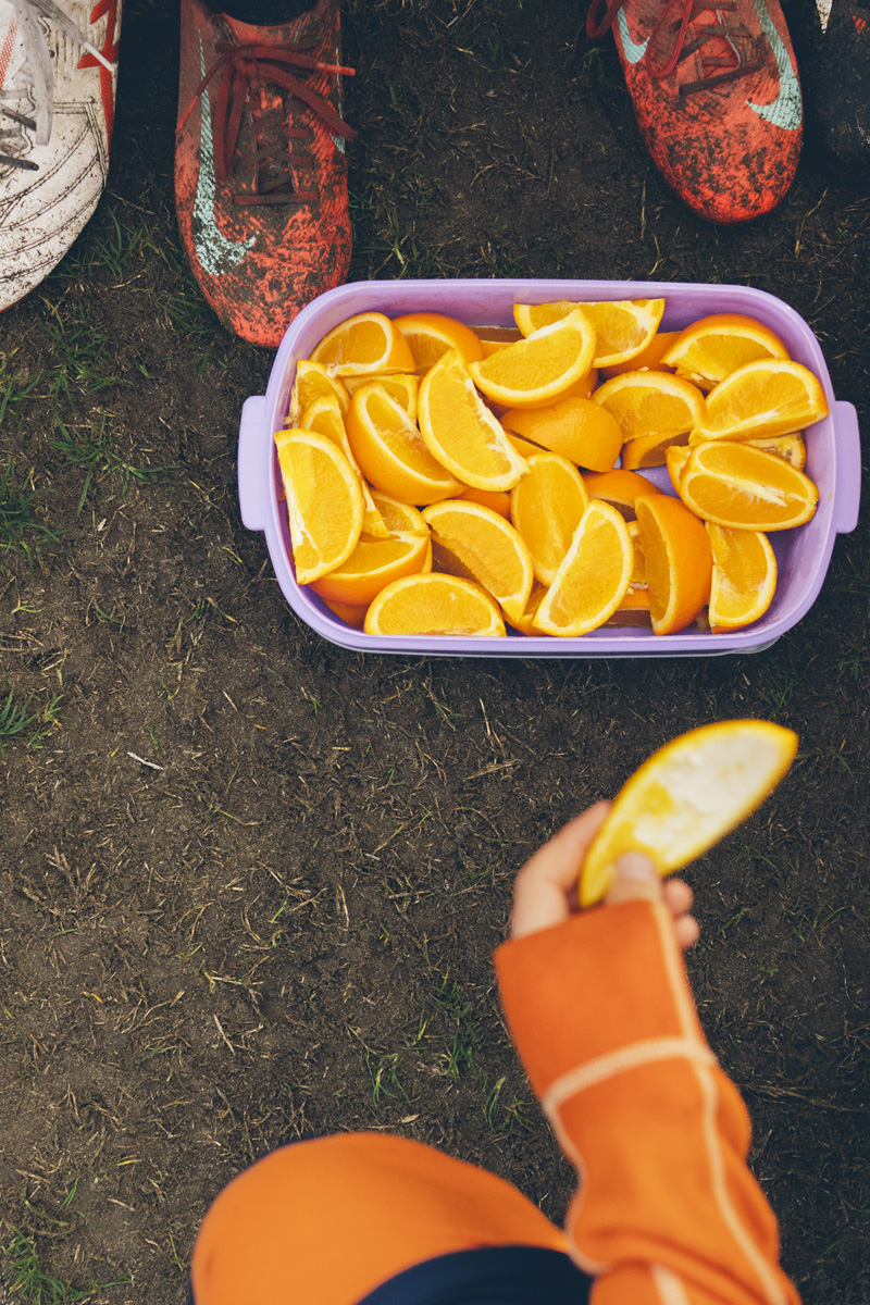Overhead shot of orange slices in a container at half time with muddy boots nearby