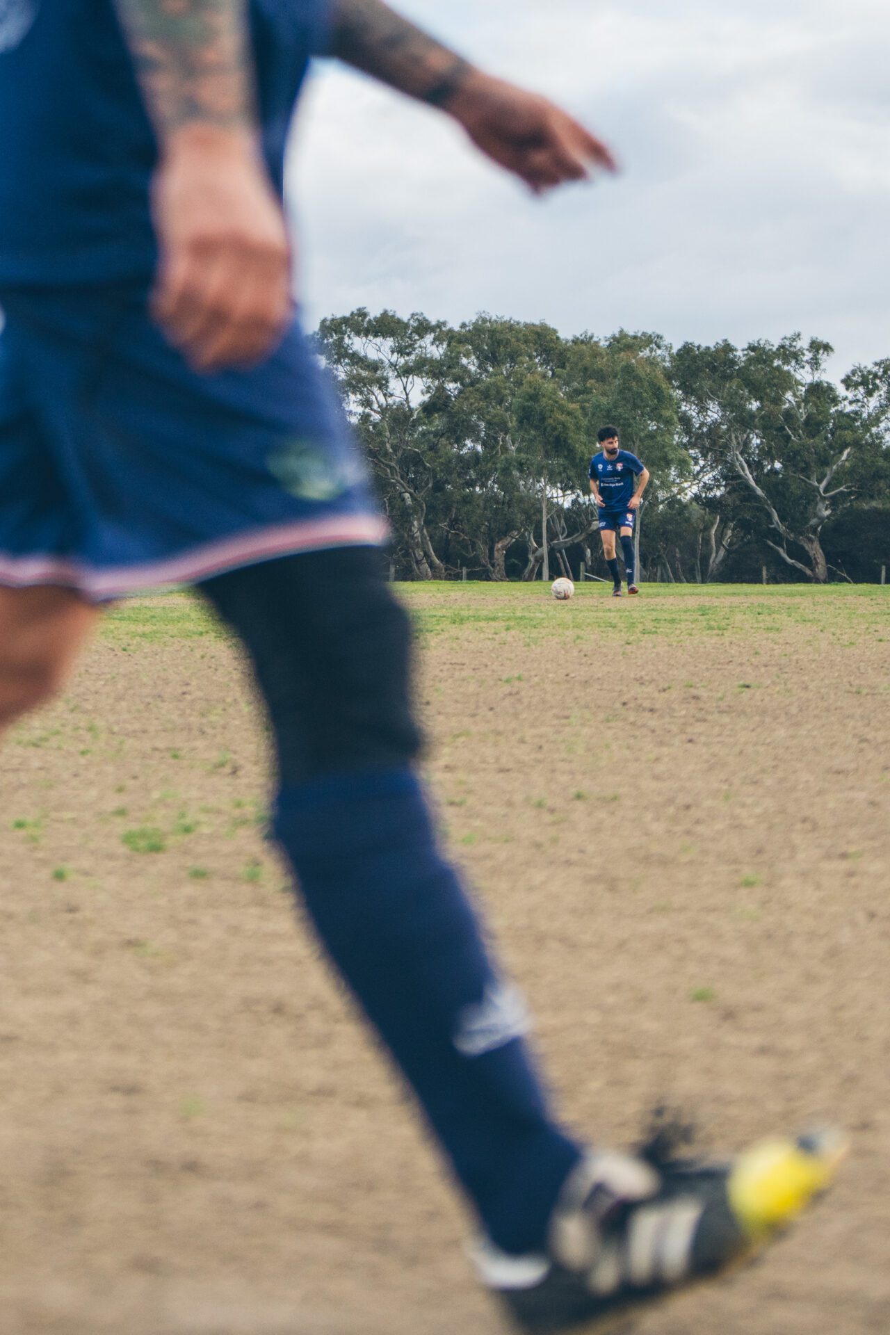 Soccer players on a large open field, one in the foreground out of focus