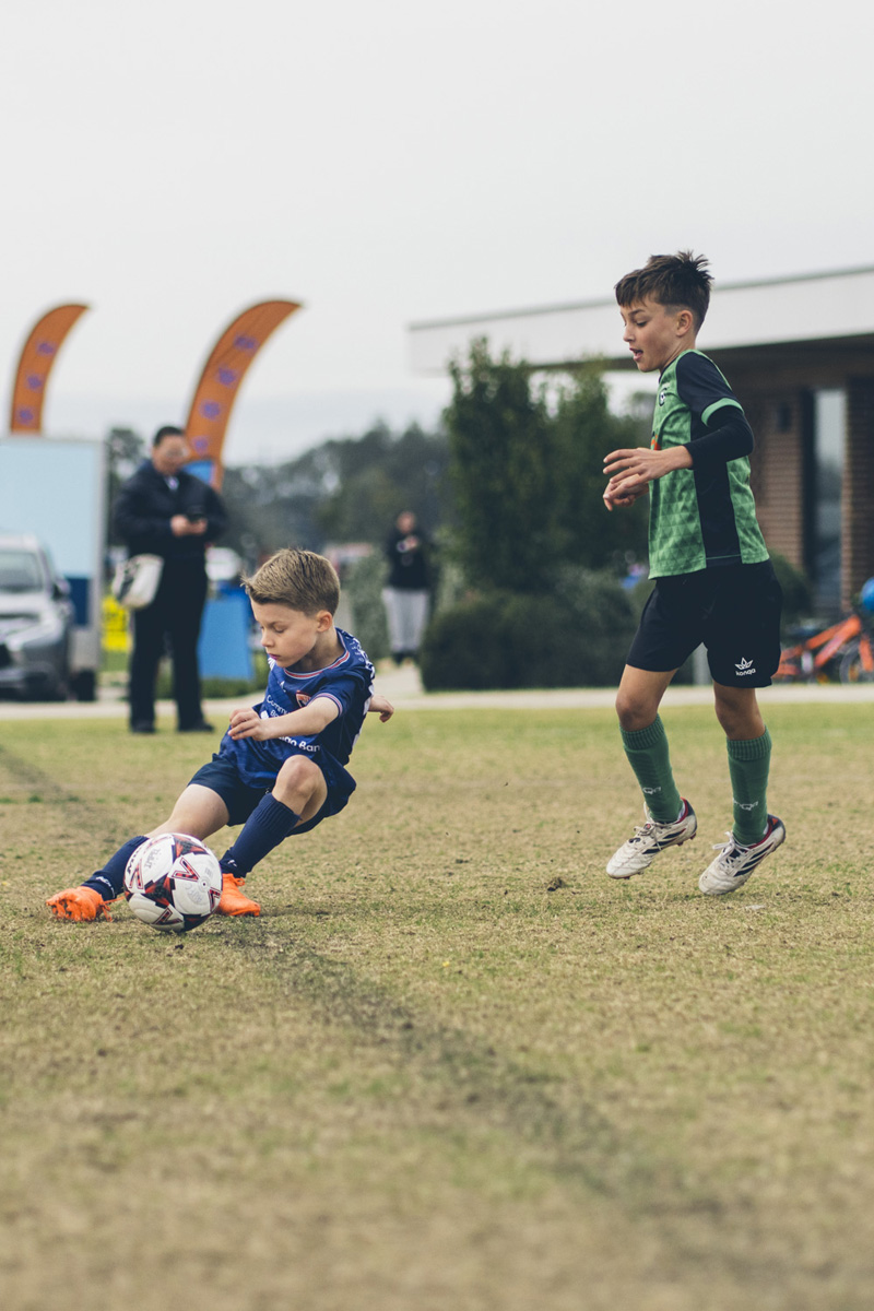 Junior soccer player sliding to control the ball during a match