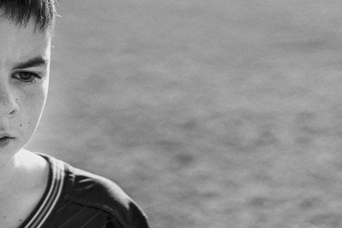 Close up black and white portrait of a junior soccer player, half his face in shadow