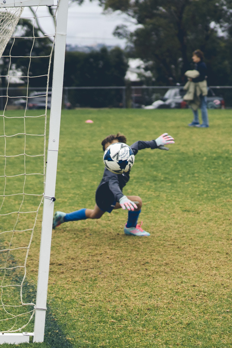 Junior goalkeeper diving to make a save during a match
