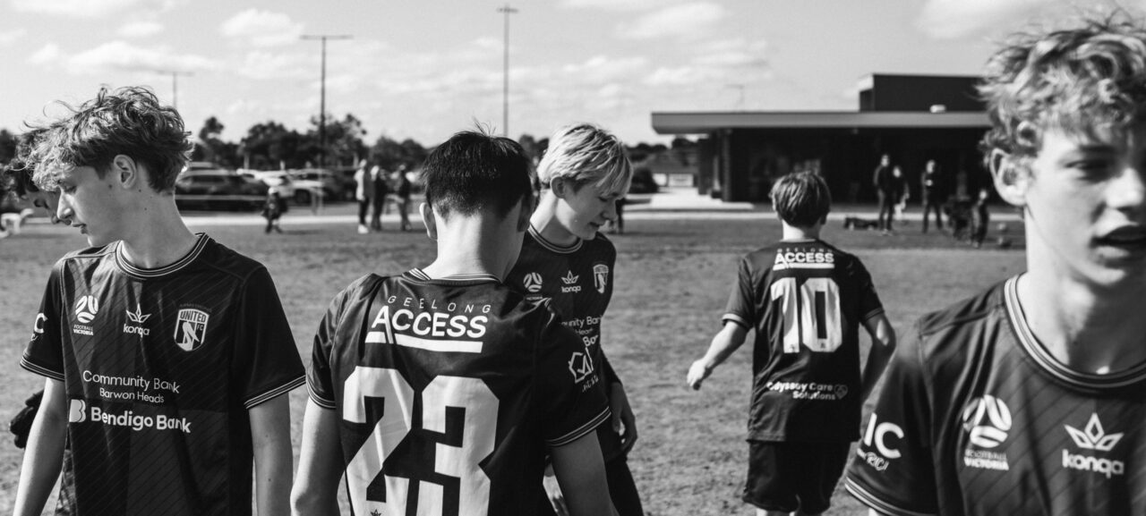 Junior soccer players walking off the field together, black and white